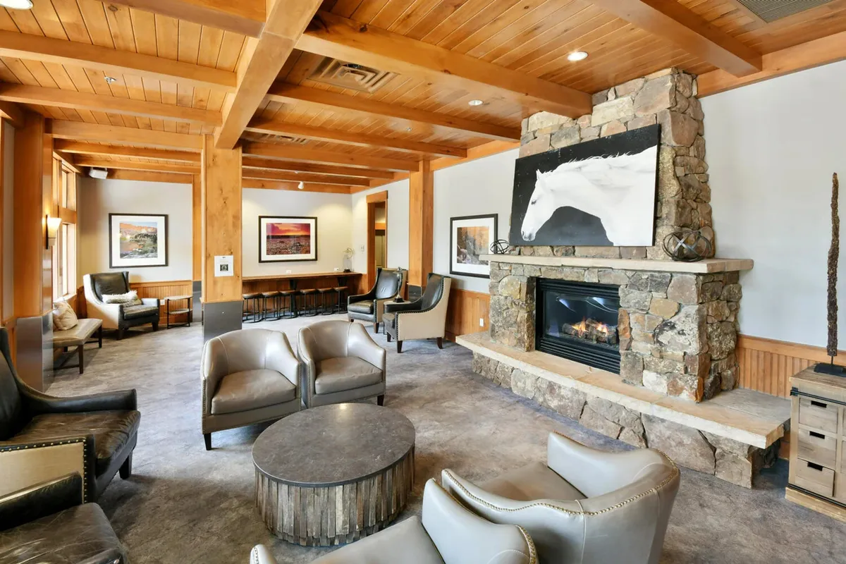 A cozy lobby lounge featuring a large stone fireplace, comfortable seating, and tasteful artwork. The ambiance is warm and inviting, ideal for relaxing, socializing, or reading by the fire after a day of adventure.